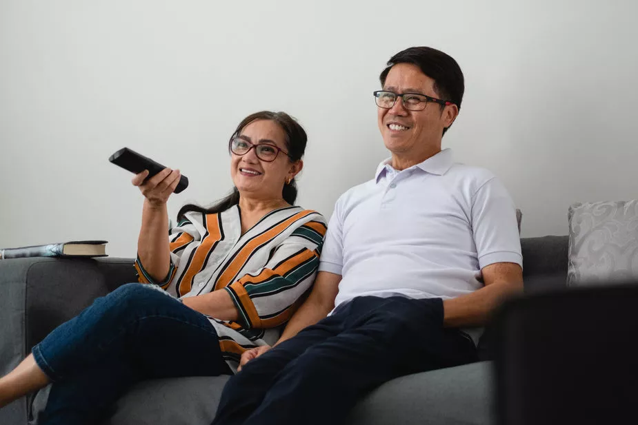 couple watches television on grey couch copy iRealty Shop Buyers